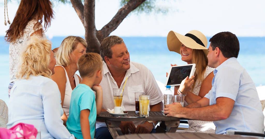 family sitting around a table on a beach vacation