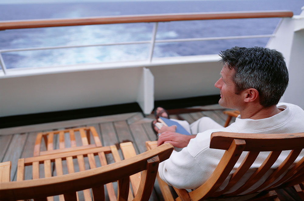 Solo passenger sitting on deckchair on cruise ship Solo cruise passenger having a relaxing day at sea