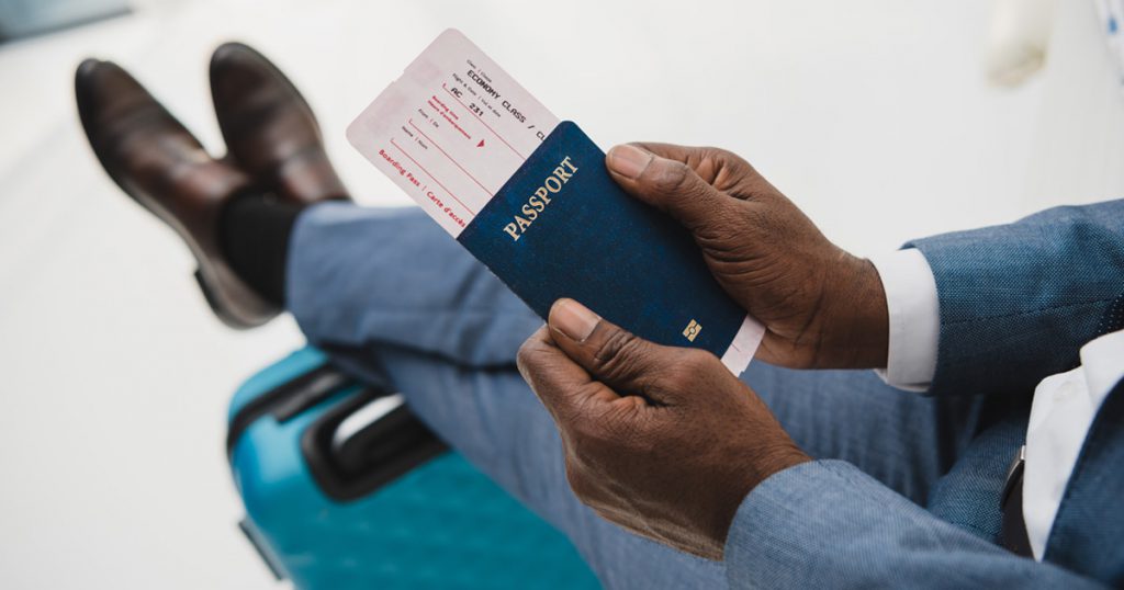 man's hands holding passport in airport