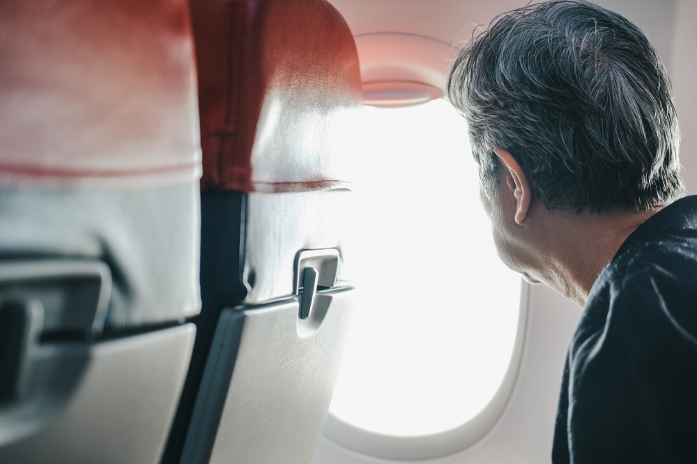 elderly senior woman looking through airplane window while traveling