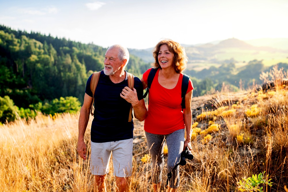 Senior tourist couple travellers hiking in nature, walking and talking