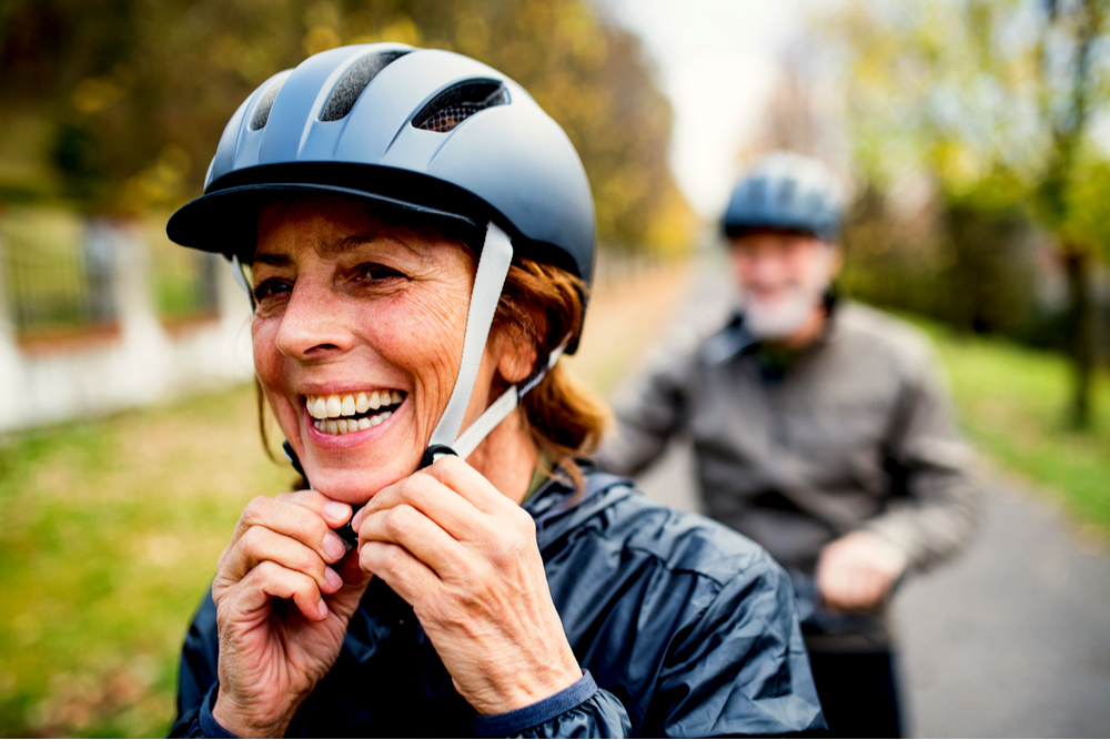 Active senior couple with bikes standing outdoors on a road in nature